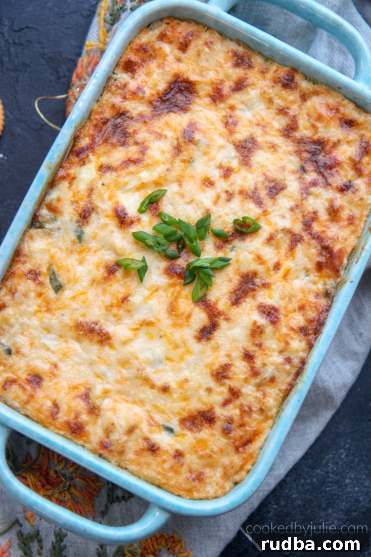 Hot crab dip in a blue baking dish, garnished with fresh herbs
