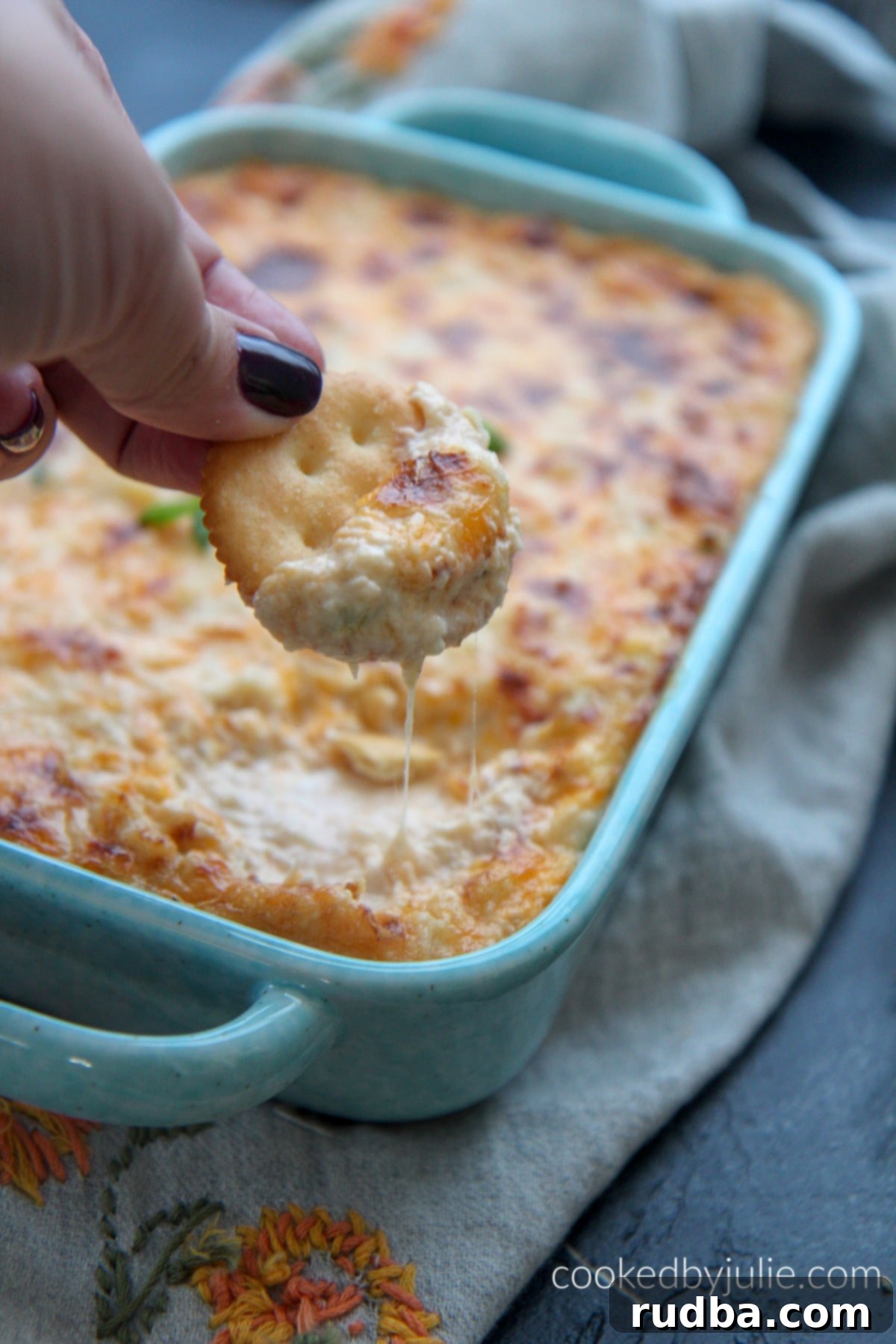 Ritz cracker with hot crab dip and fresh green onion garnish