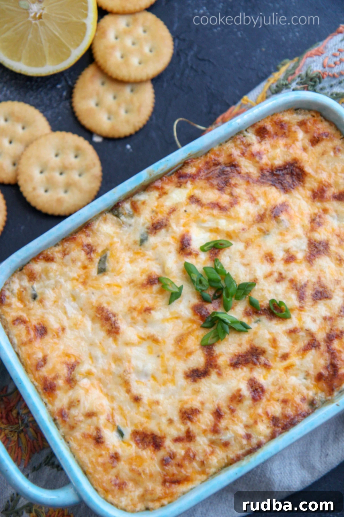 Crab dip garnished with green onions and served with Ritz crackers.
