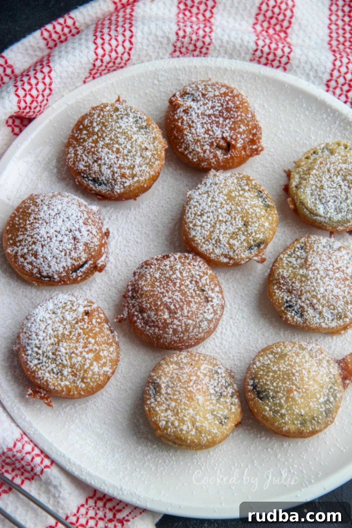 deep fried oreos with powdered sugar on a white plate and red and white towel on the side 