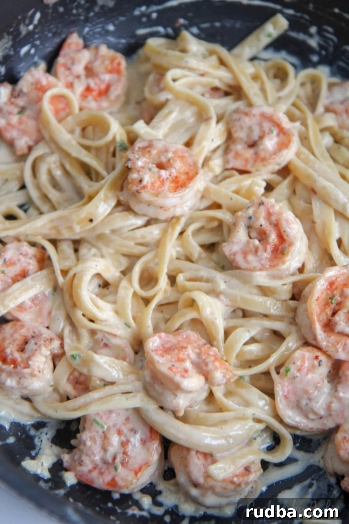 shrimp and fettuccine alfredo pasta tossed in a black skillet