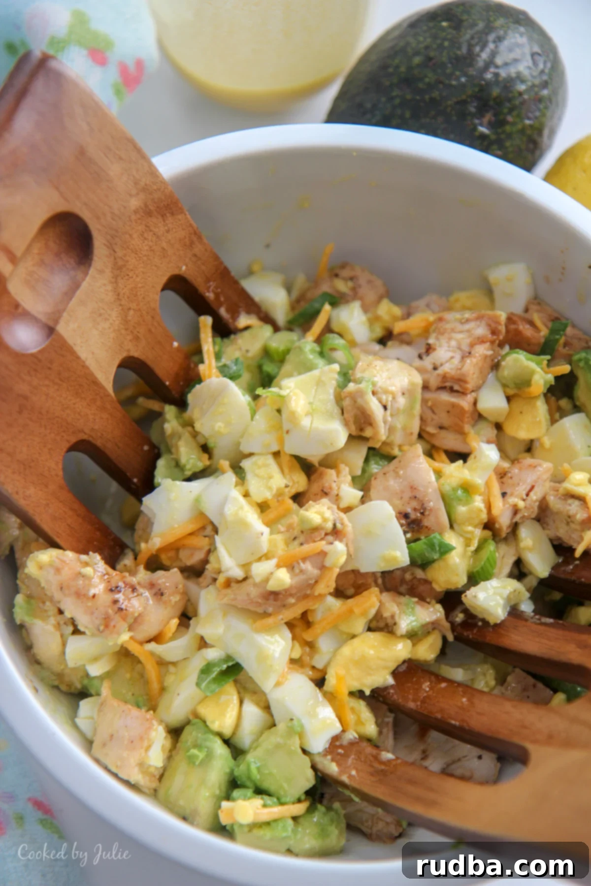 avocado chicken salad in a white bowl and wooden salad mixers 