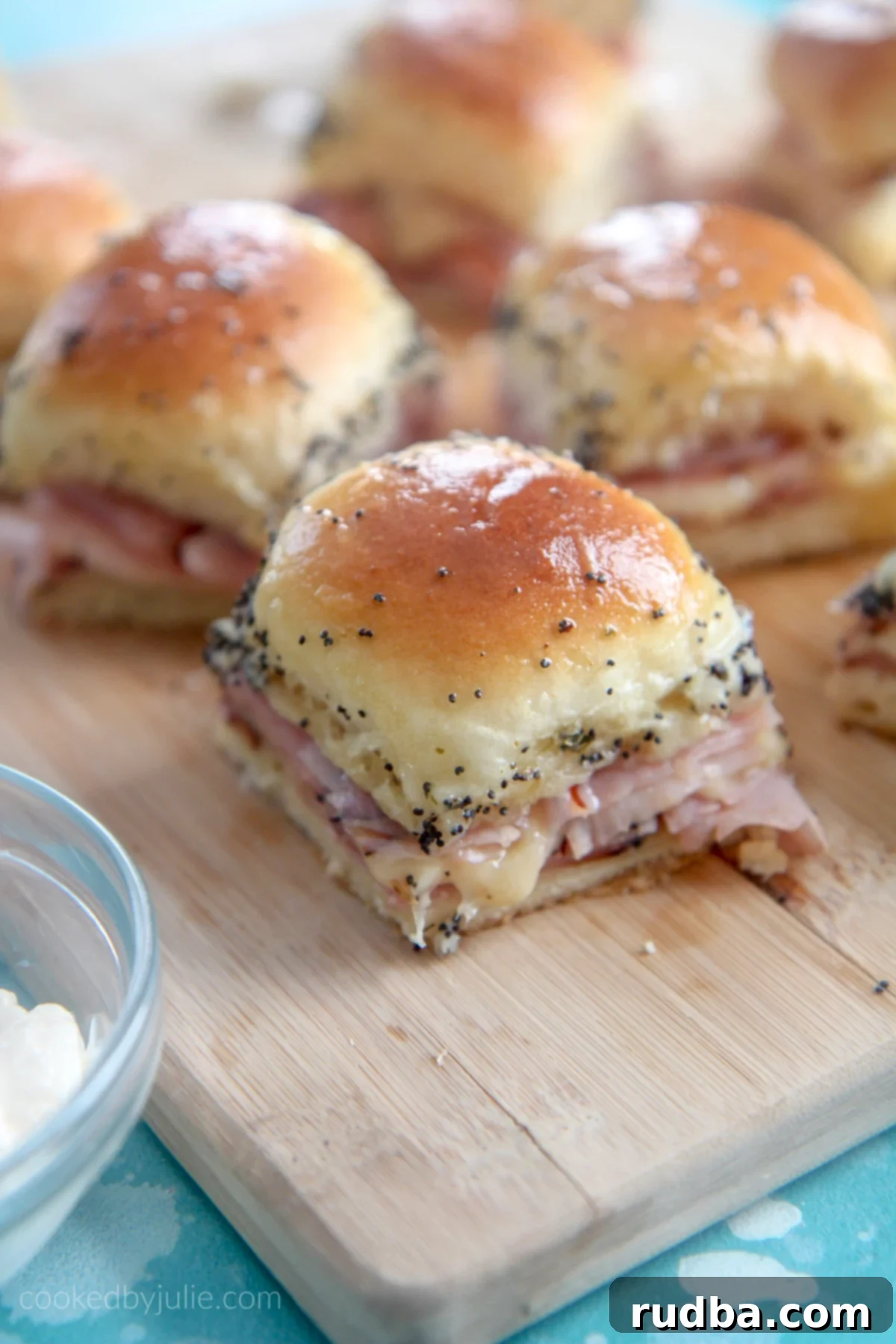 ham and cheese sliders on a wooden board with mayo on the side 