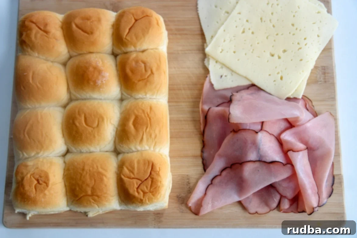 Hawaiian soft rolls with ham and cheese on a wooden board