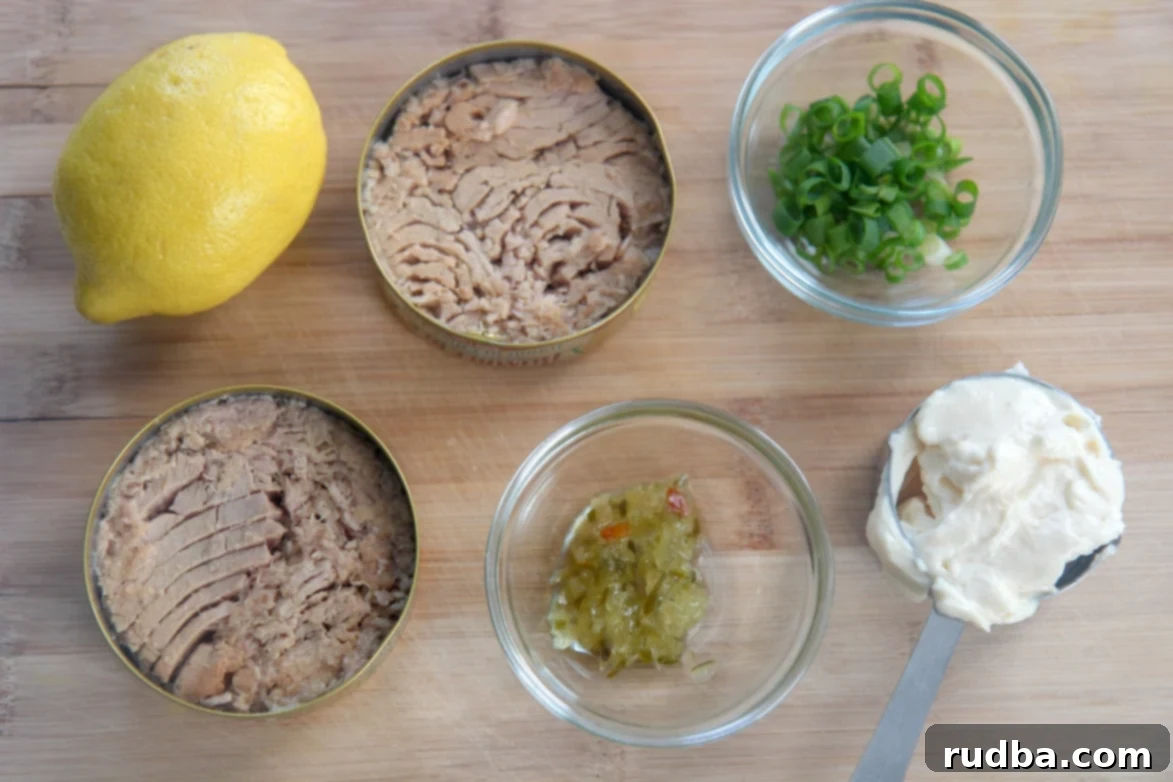 canned tuna, lemon, sweet relish, mayo, and scallions in small bowls on a wooden board