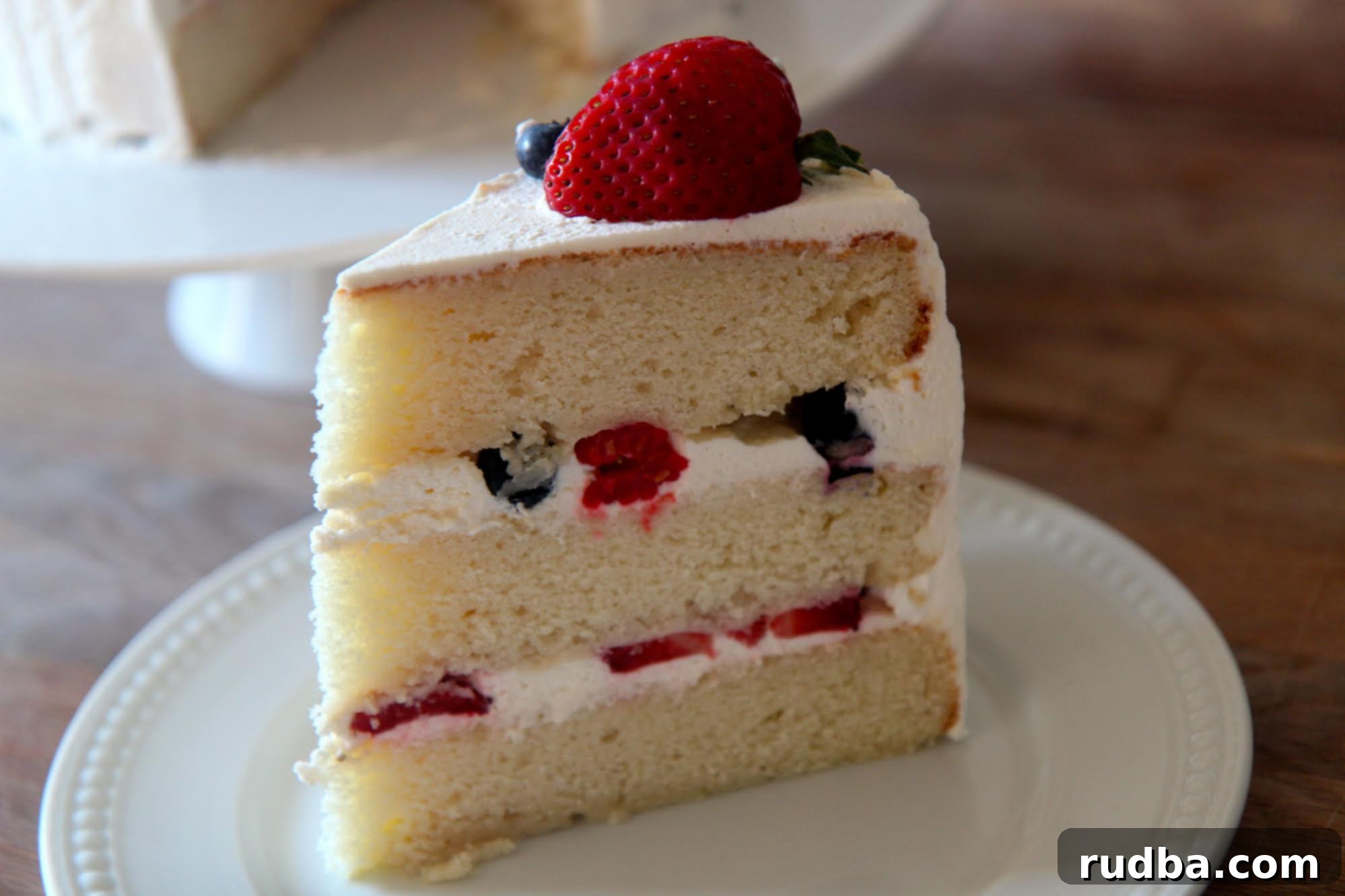 Three layers of yellow cake with a sweet vanilla frosting and filled with raspberries, strawberries, and blueberries