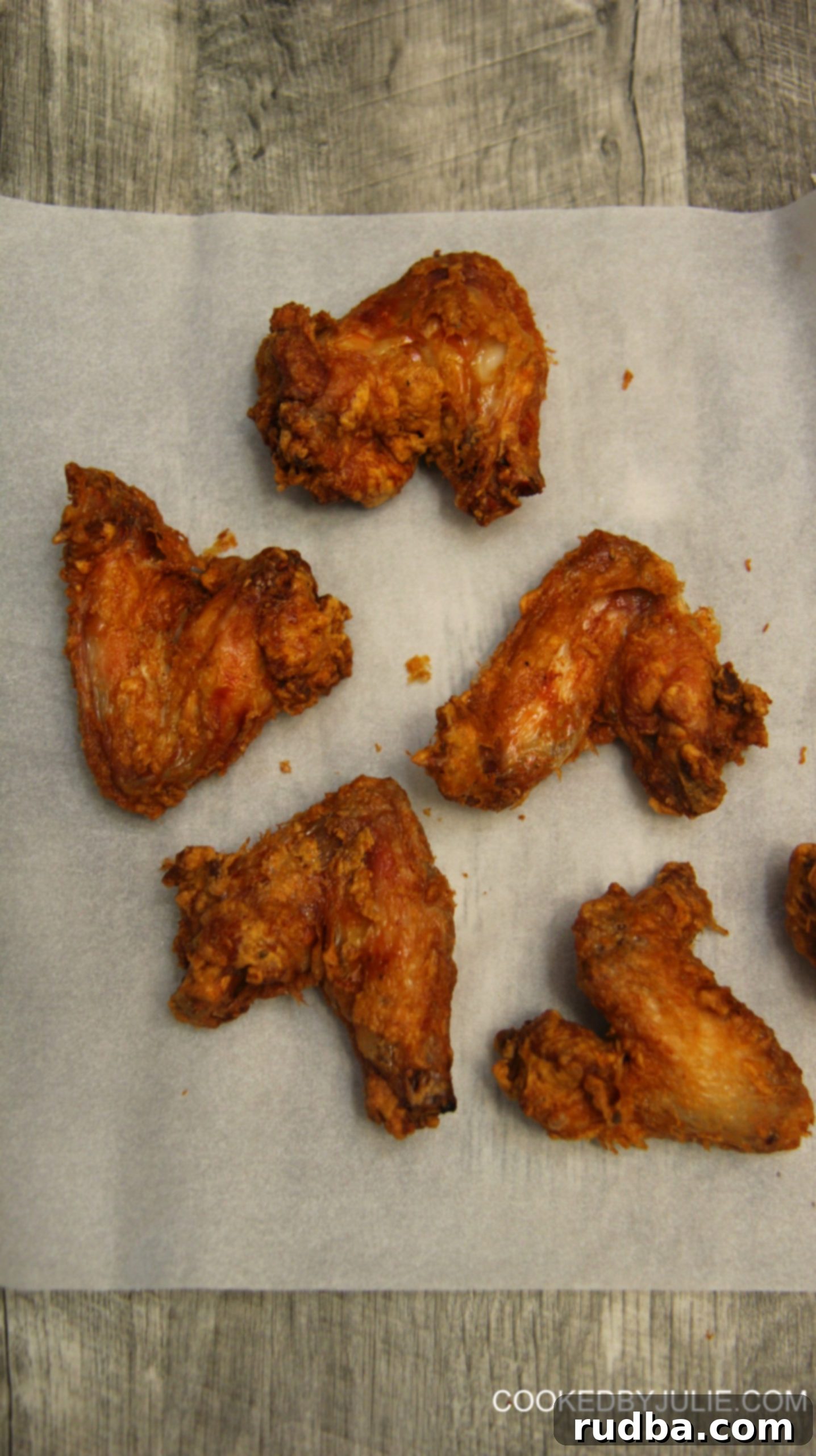 Close-up of golden-brown crispy chicken wings with a vibrant red hot sauce drizzle, showcasing the perfect texture achieved through brining.