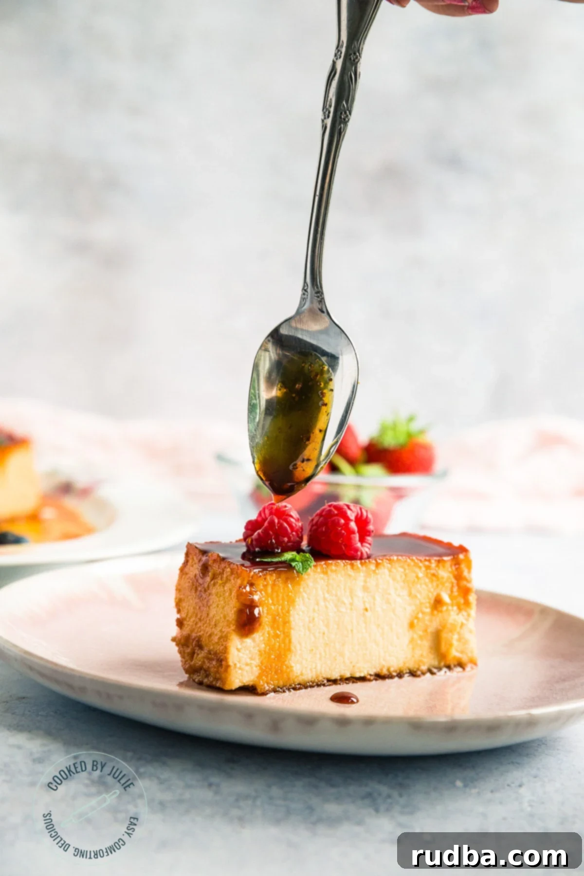 Crème Caramel 4 A perfect slice of caramel custard flan on a delicate pink plate, with a spoon gently drizzling more luscious caramel sauce over its smooth surface.