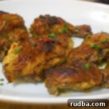 Close-up of golden brown Pollo Asado with fresh herbs.