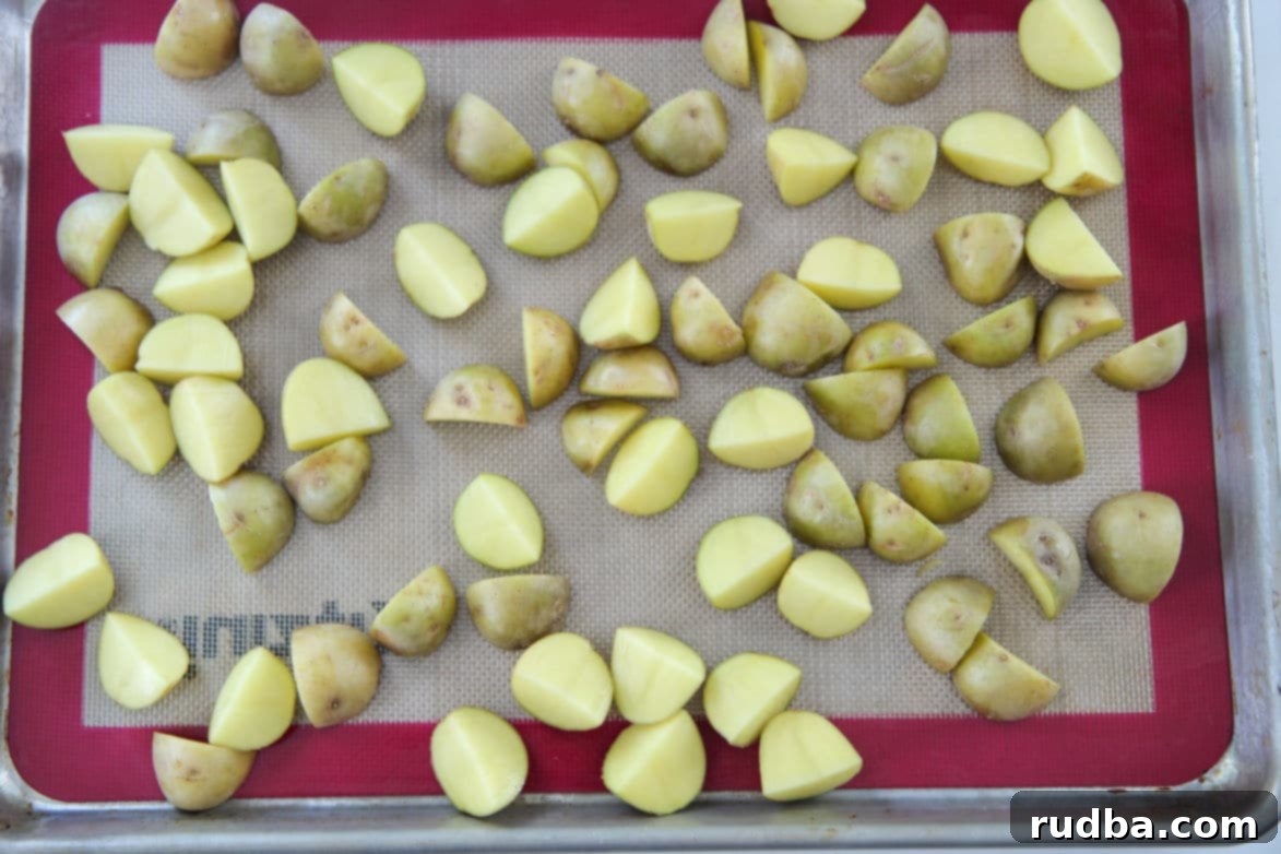 Close-up shot of seasoned yellow baby potatoes laid out evenly on a baking sheet, coated in spices and olive oil, ready for roasting.