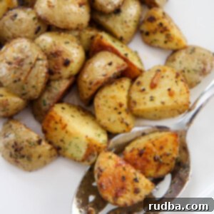 two potatoes on a slotted spoon on a white plate with more potatoes around the spoon.