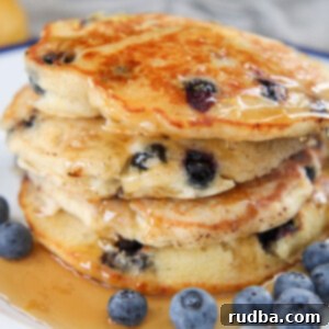 Lemon Blueberry Pancakes 5 stacked pancakes with syrup and blueberries on the side
