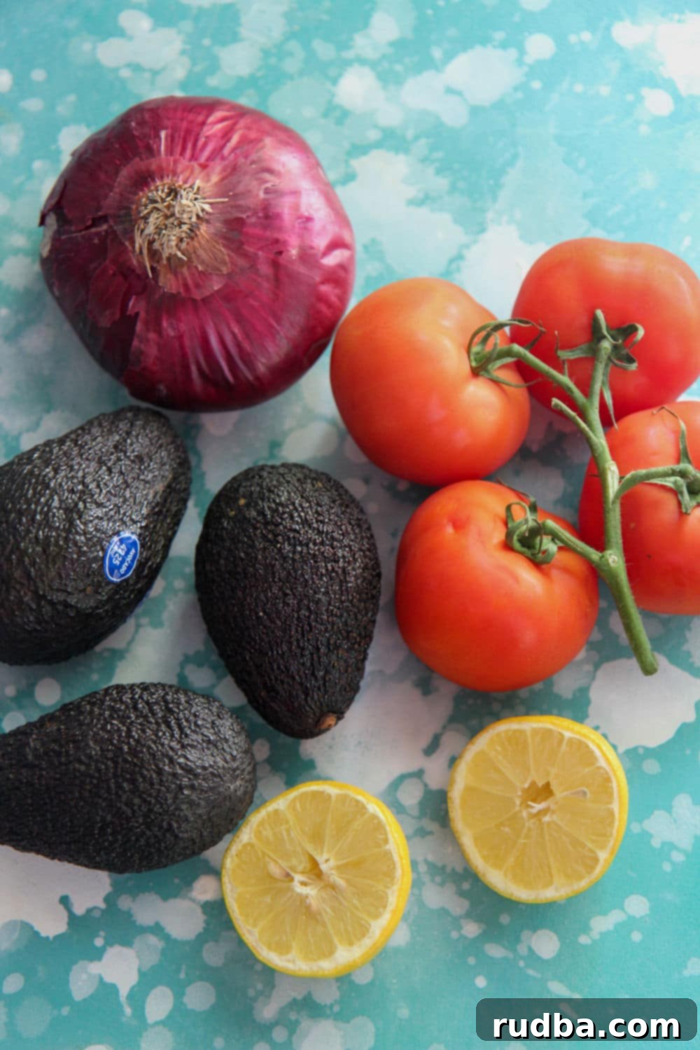 a red onion, a lemon, avocados, and tomatoes on a blue board 
