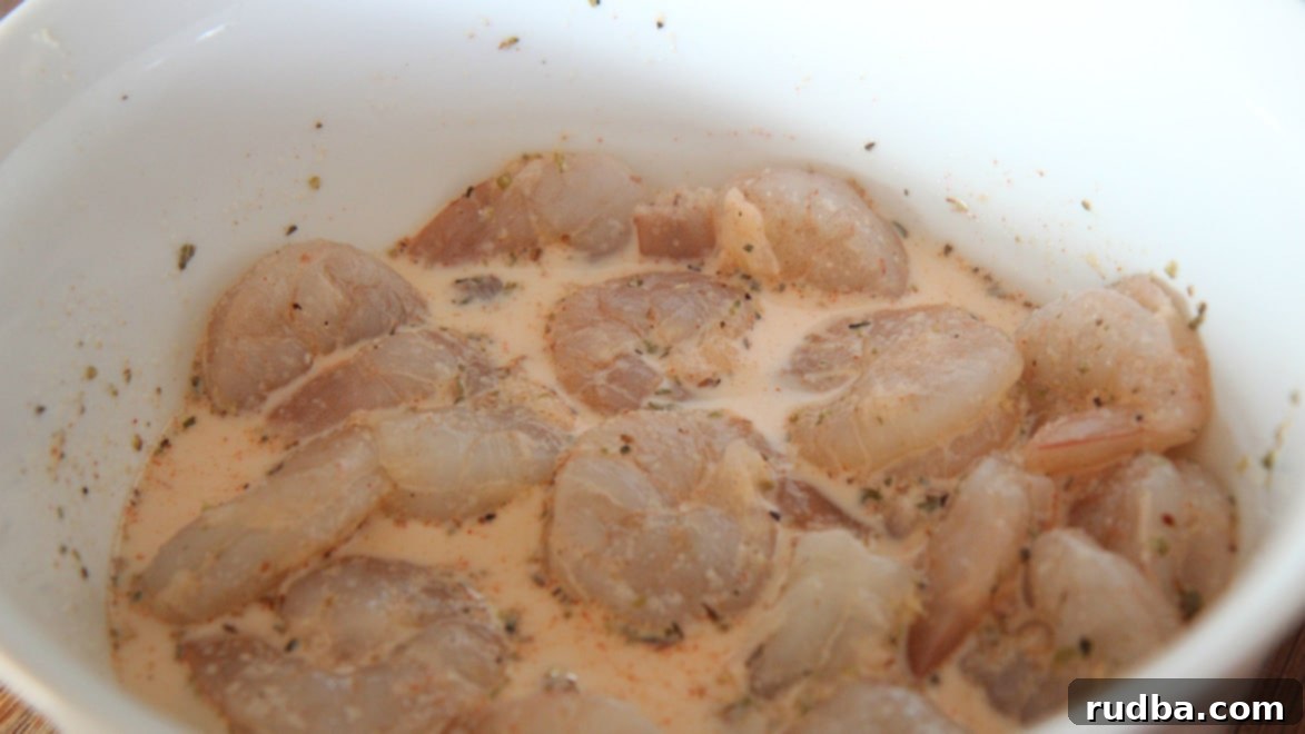 raw shrimp, spices, and milk in a white bowl. 