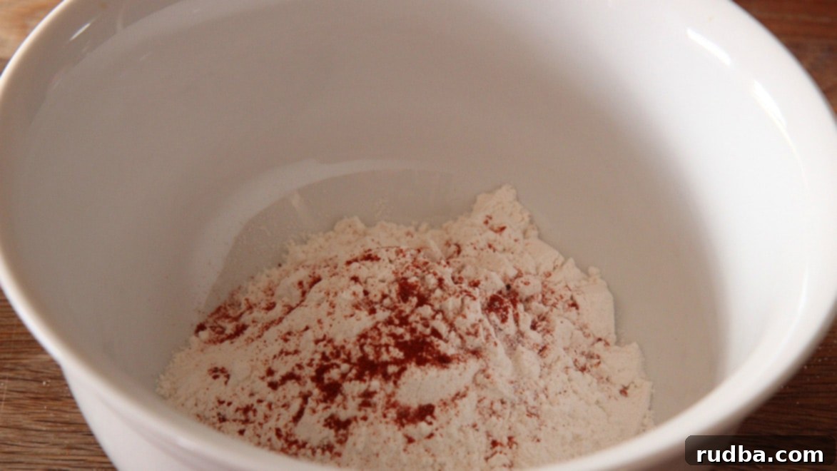 all-purpose flour, paprika, granulated garlic, oregano, salt, and pepper in a white bowl. 