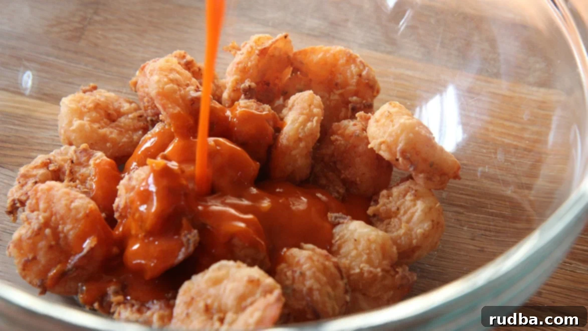 fried shrimp in a bowl with buffalo sauce poured on top