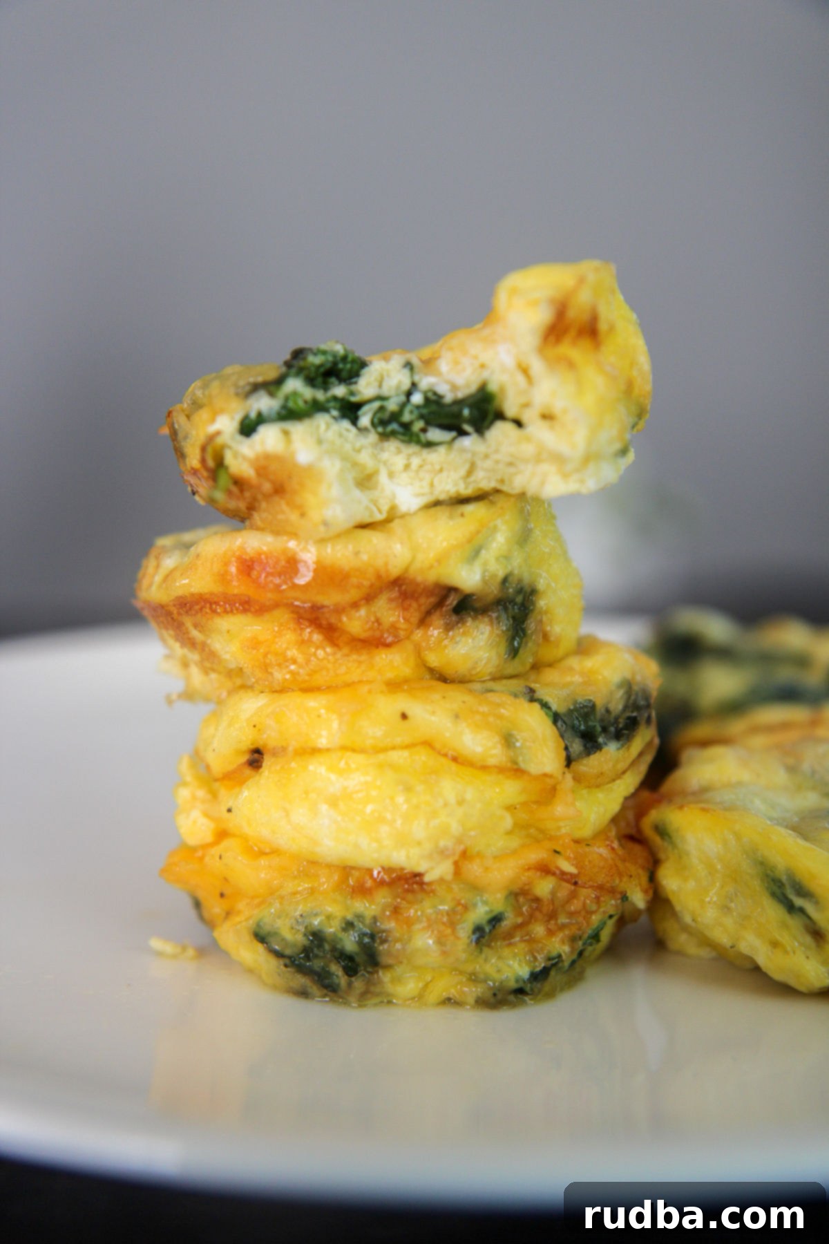 egg muffins stacked on a white plate, garnished with fresh herbs