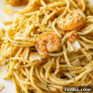 Vibrant Pesto Pasta with Succulent Shrimp 5 shrimp pesto spaghetti on a white plate up close.