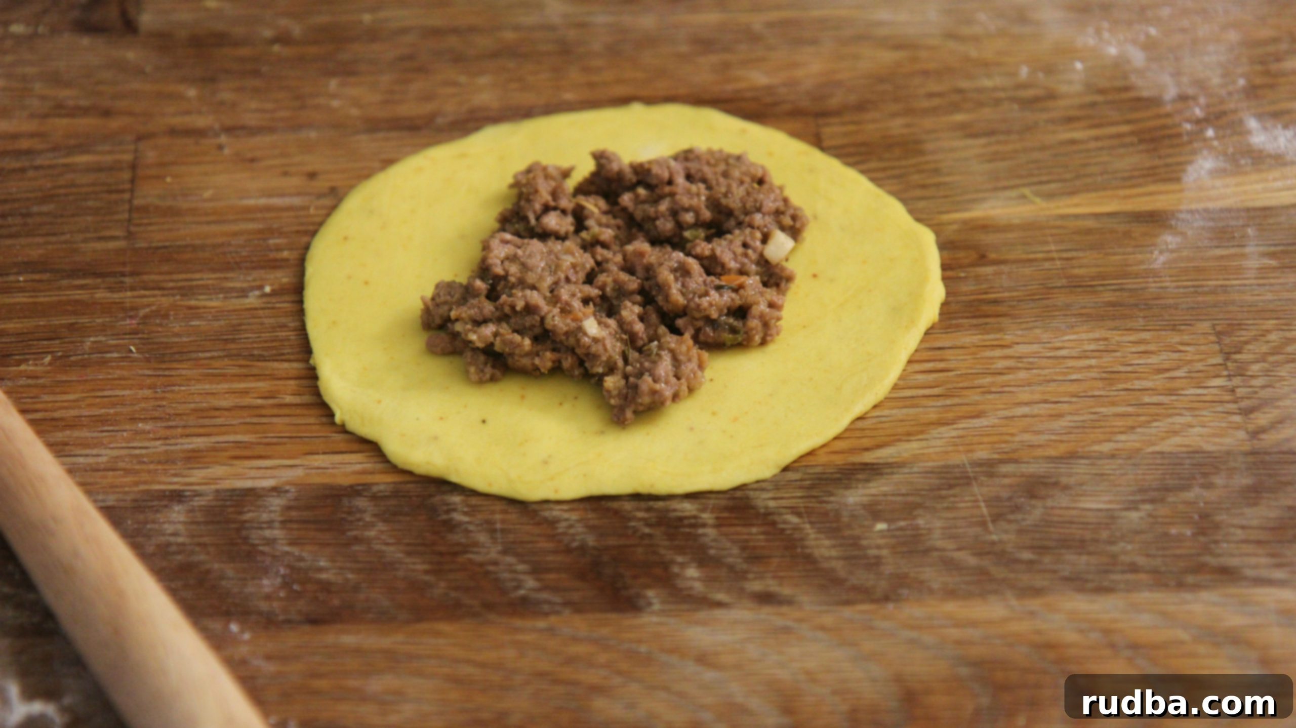 a disc of yellow dough with cooked ground beef. 