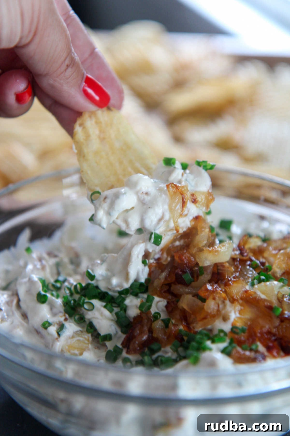 Person holding a chip over a bowl of French onion dip