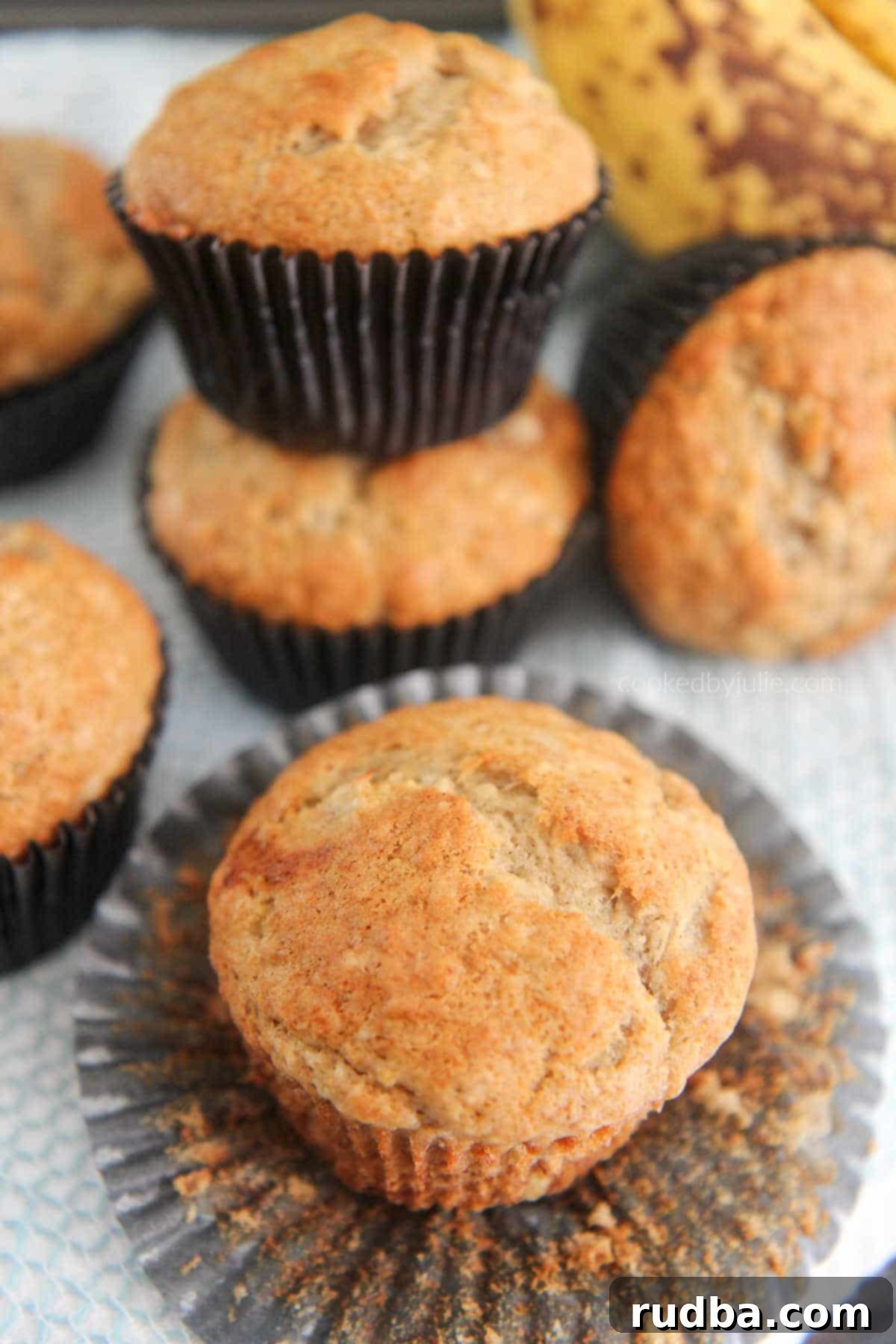 Soft and moist banana muffins with fresh bananas in the background, ready to be enjoyed.