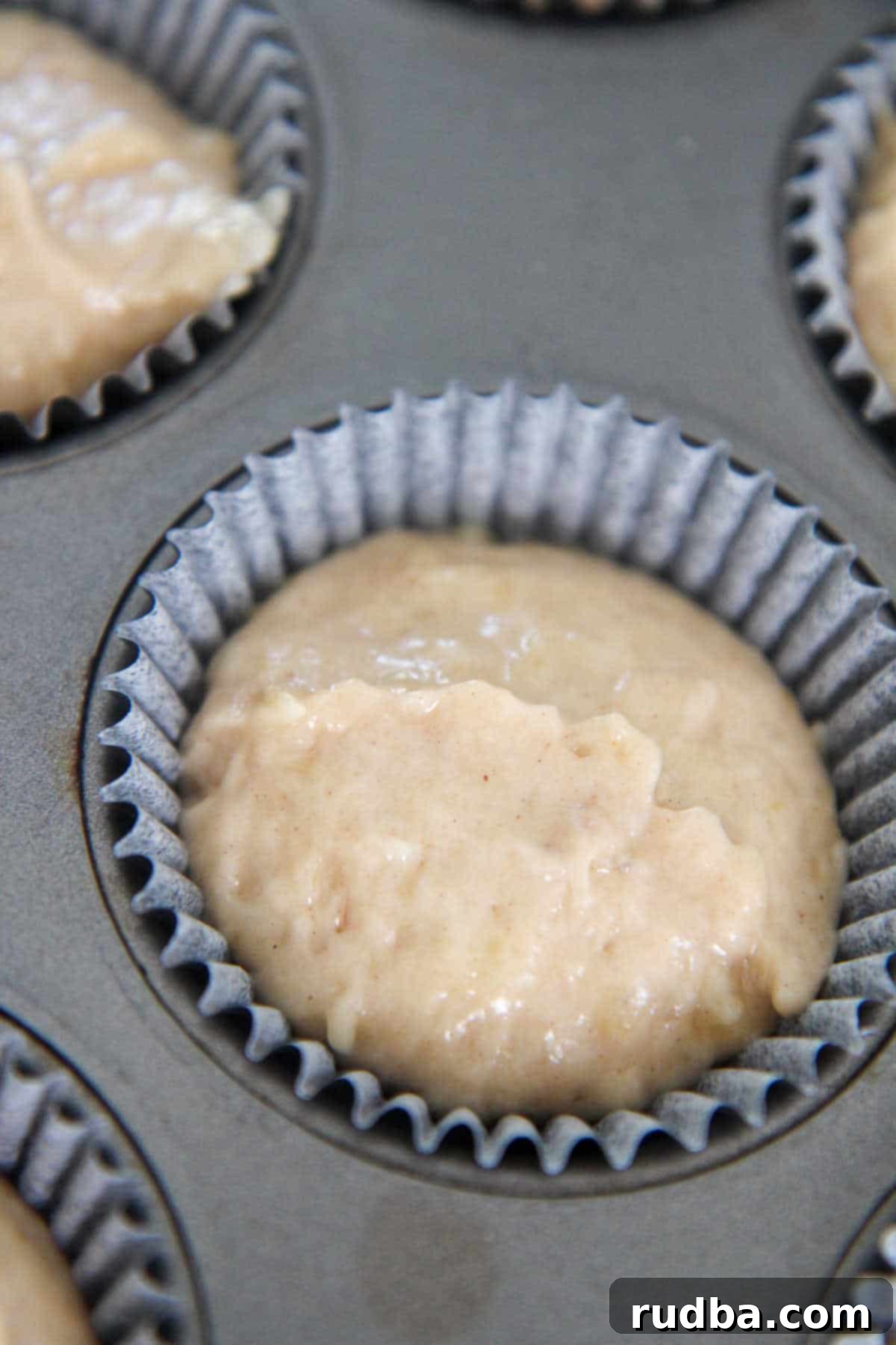 Close-up of banana muffin batter in a cupcake liner, ready for baking.