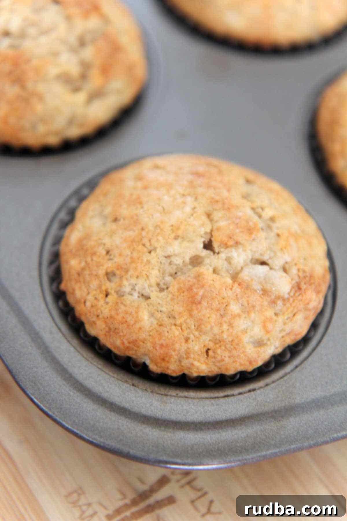 Freshly baked golden brown banana muffins in a muffin tin, cooling down.