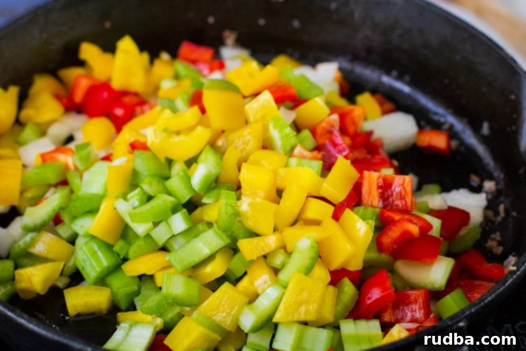 peppers, celery, and onions cooking in a cast iron skillet 
