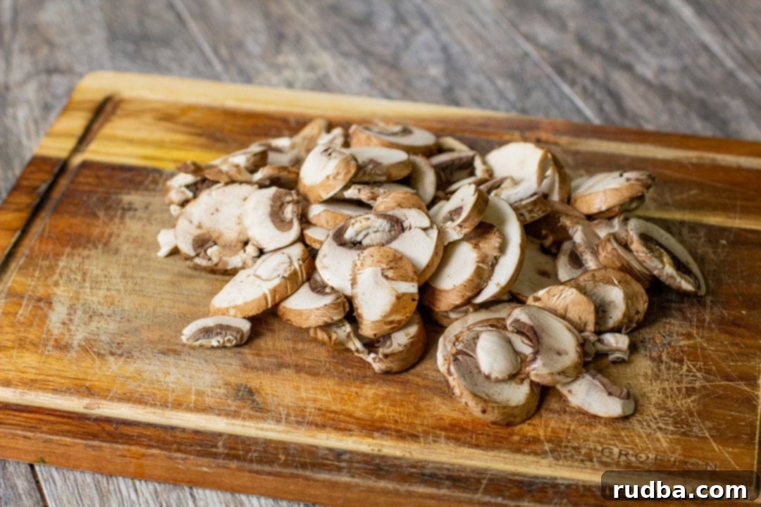 Finely chopped cremini mushrooms on a wooden cutting board, ready for sautéing