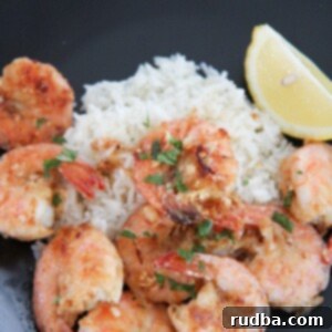 Hawaiian garlic shrimp, white rice, and lemon on a black plate