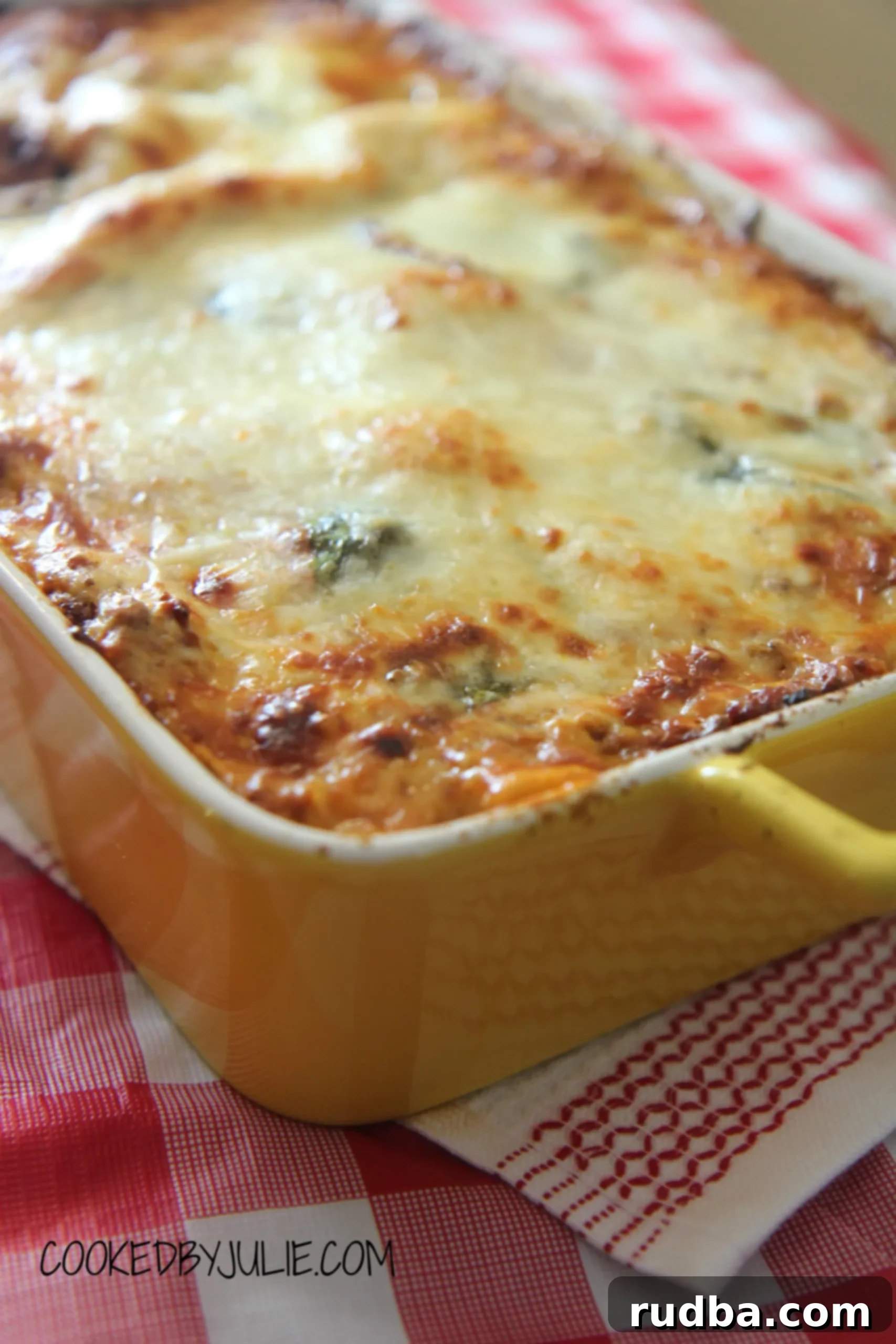 Classic lasagna in a yellow casserole baking dish, served on a white and red striped towel, ready to be enjoyed.