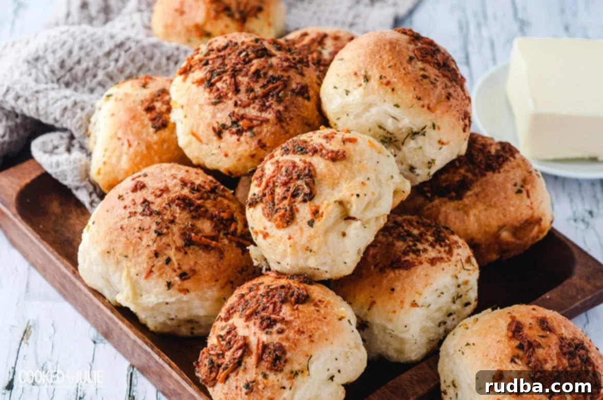 garlic parmesan dinner rolls on a wooden board with butter on the side