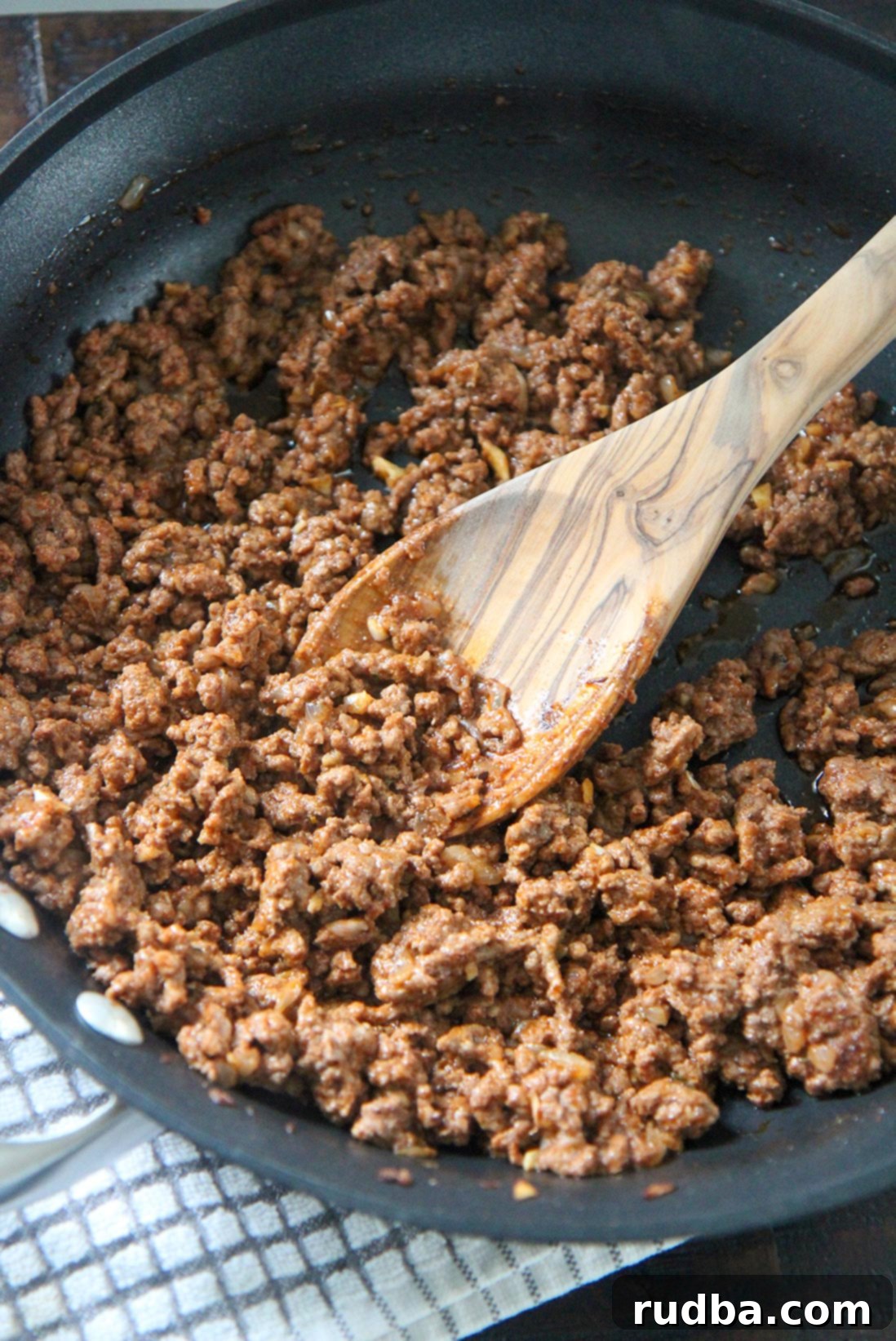 ground beef in a skillet with a wooden spoon 