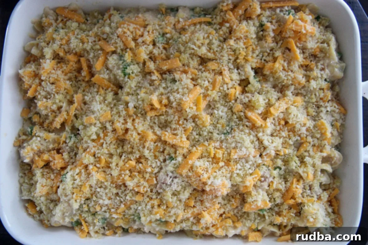 Unbaked tuna noodle casserole in a white baking dish topped with breadcrumbs and cheese