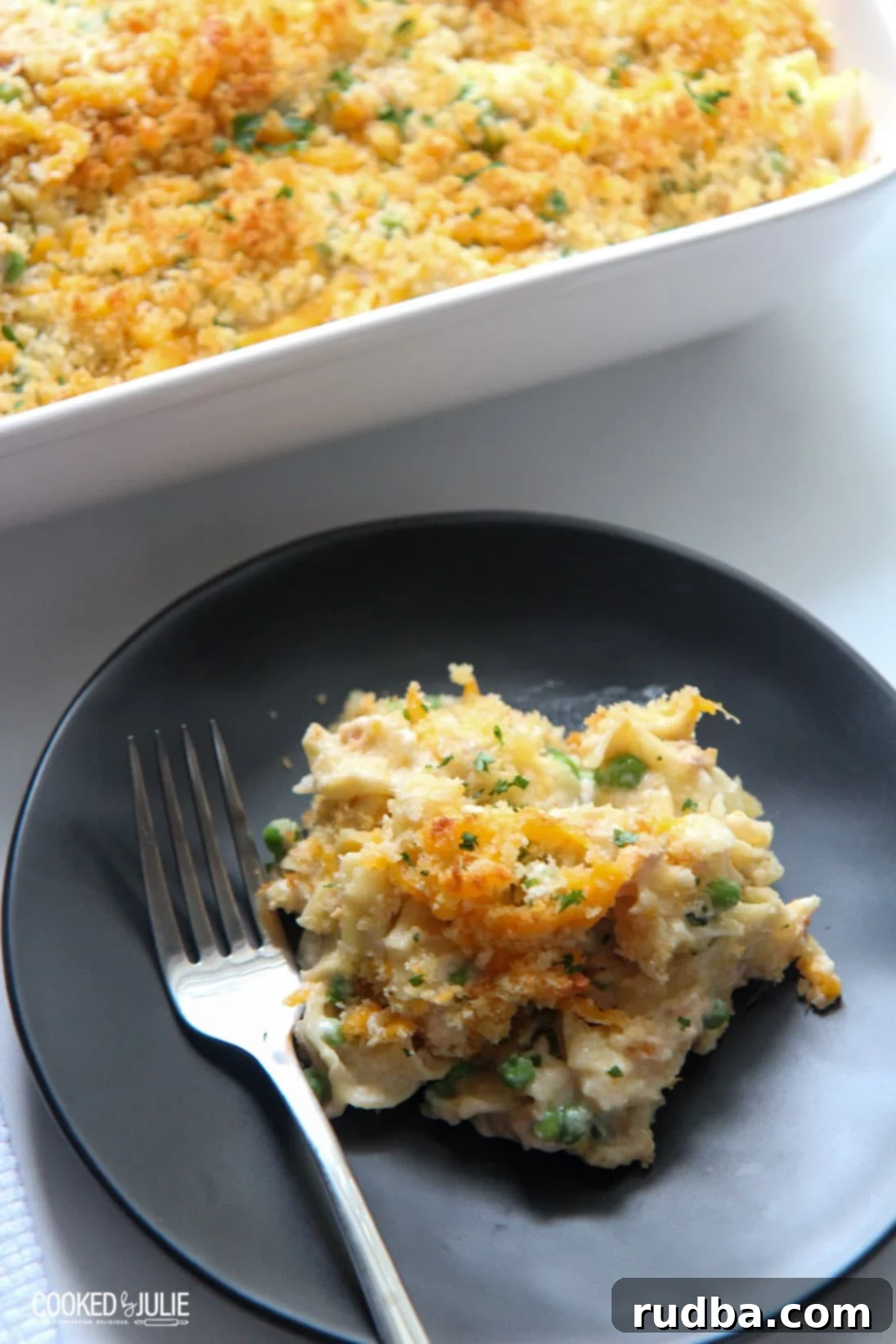 A small black plate with a portion of creamy tuna noodle casserole and a fork