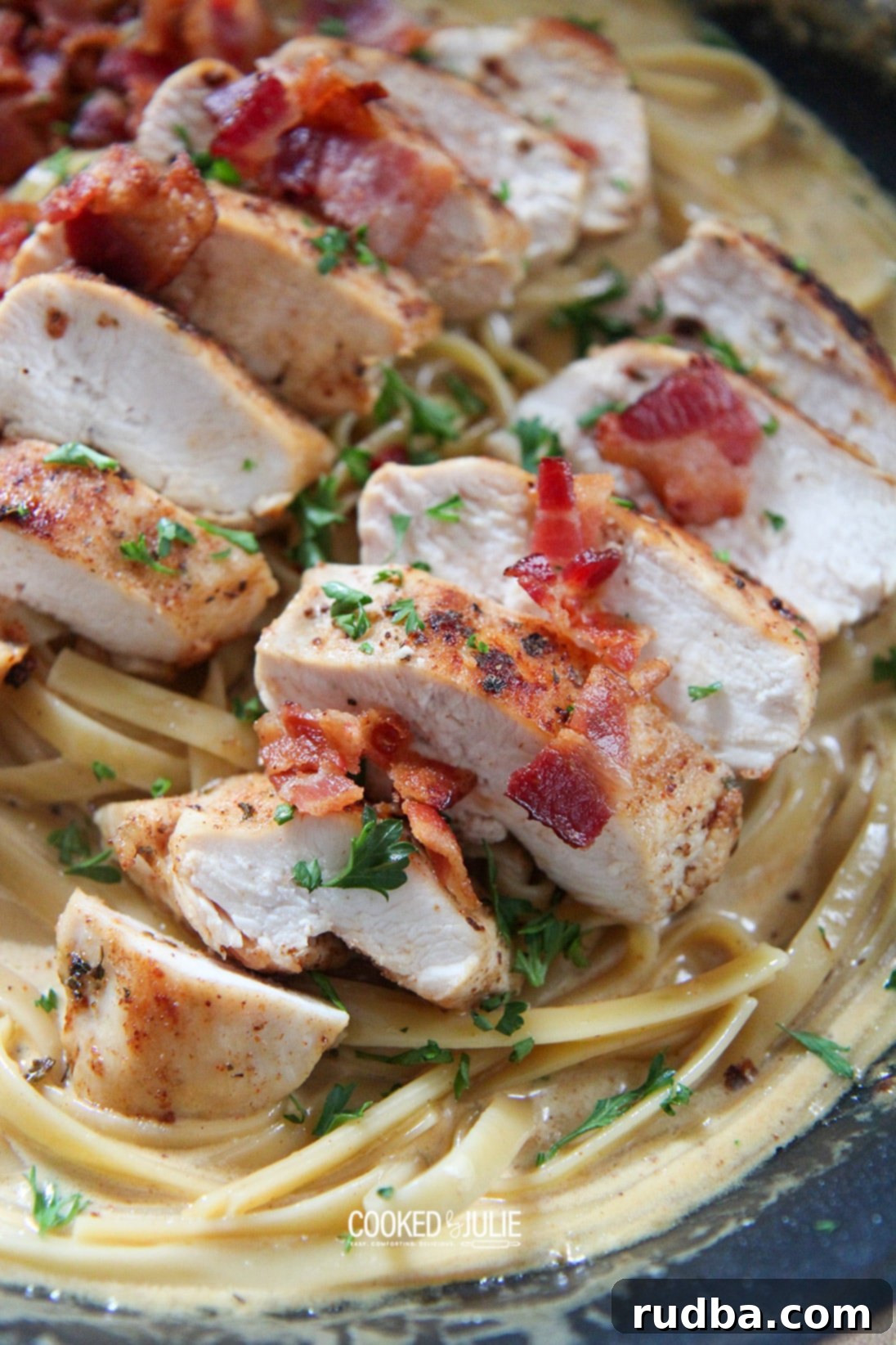 Creamy chicken, bacon, and fettuccine pasta in a black skillet, ready to be served.