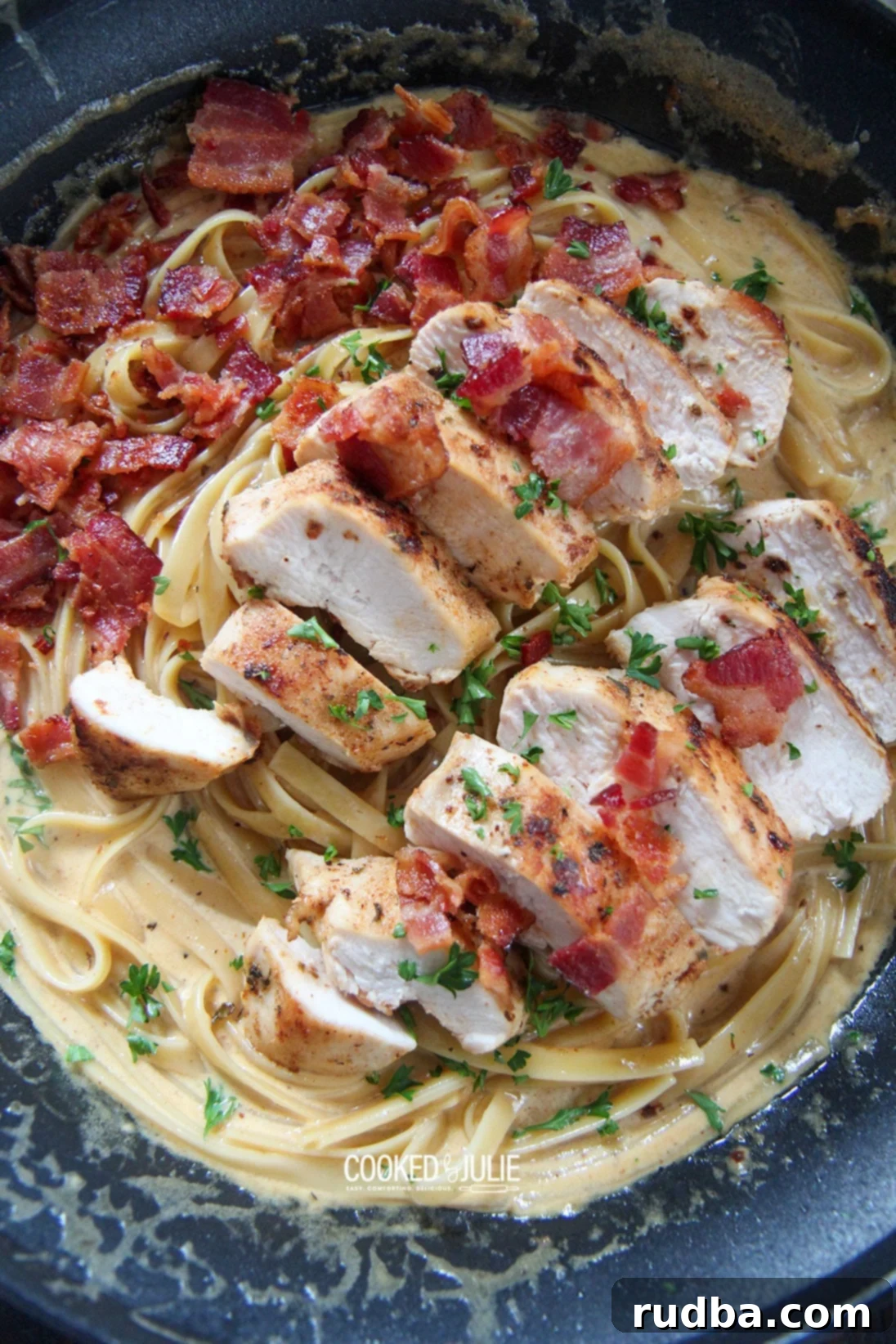 pasta in a skillet with sauce, chicken, and bacon before serving