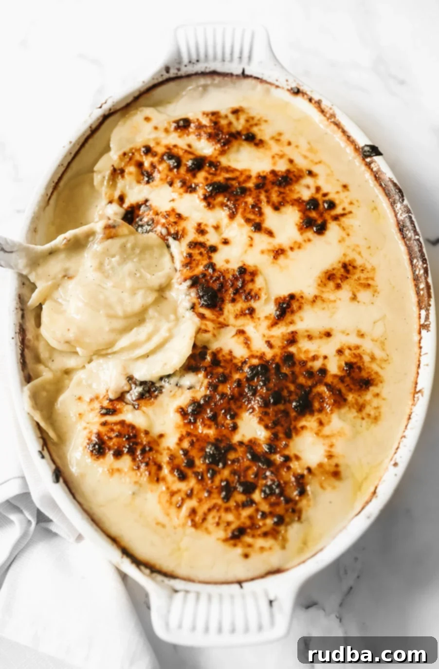 Creamy Cheesy Scalloped Potatoes 2 scalloped potatoes in a white casserole dish.