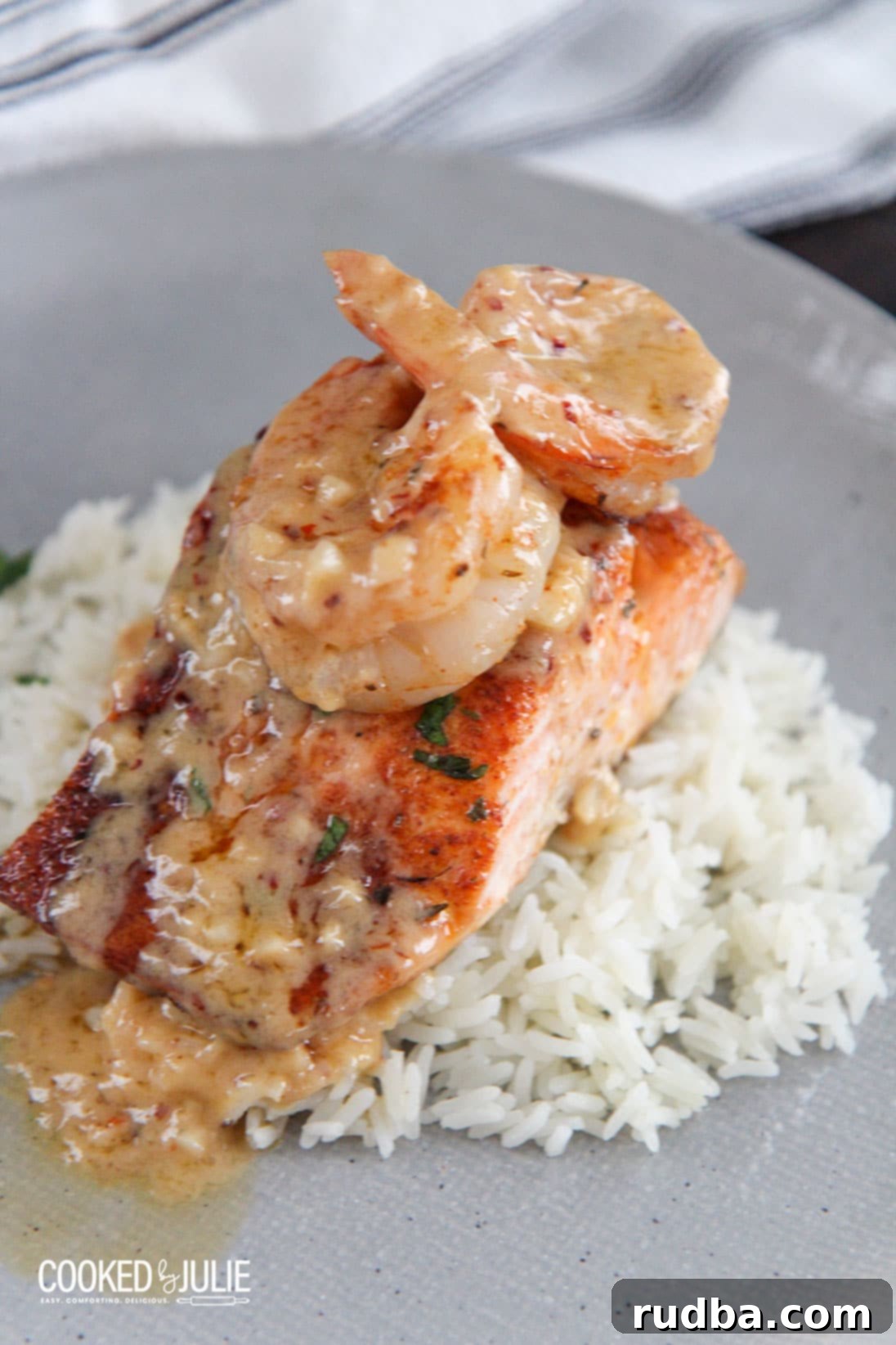 Salmon and shrimp over white rice on a plate with creamy sauce