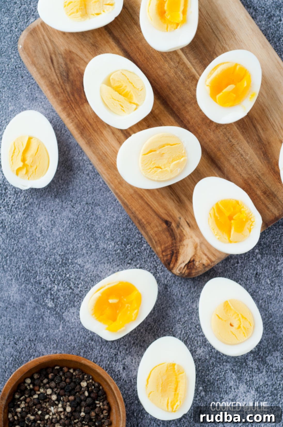 Two halves of a perfectly hard-boiled egg sprinkled with salt and pepper, beside small bowls of seasoning