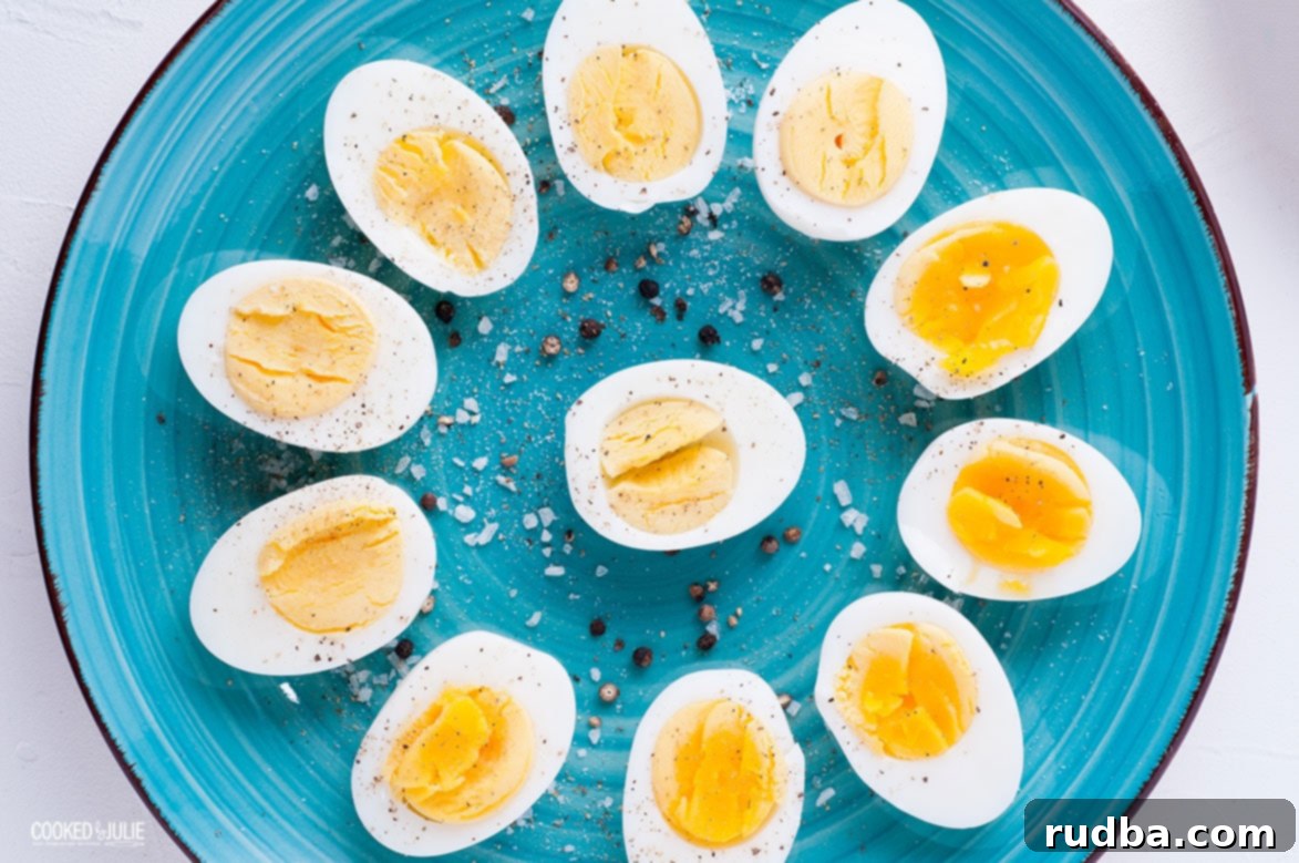 Sliced soft and hard-boiled eggs arranged in a flower pattern on a teal plate, garnished with salt and pepper