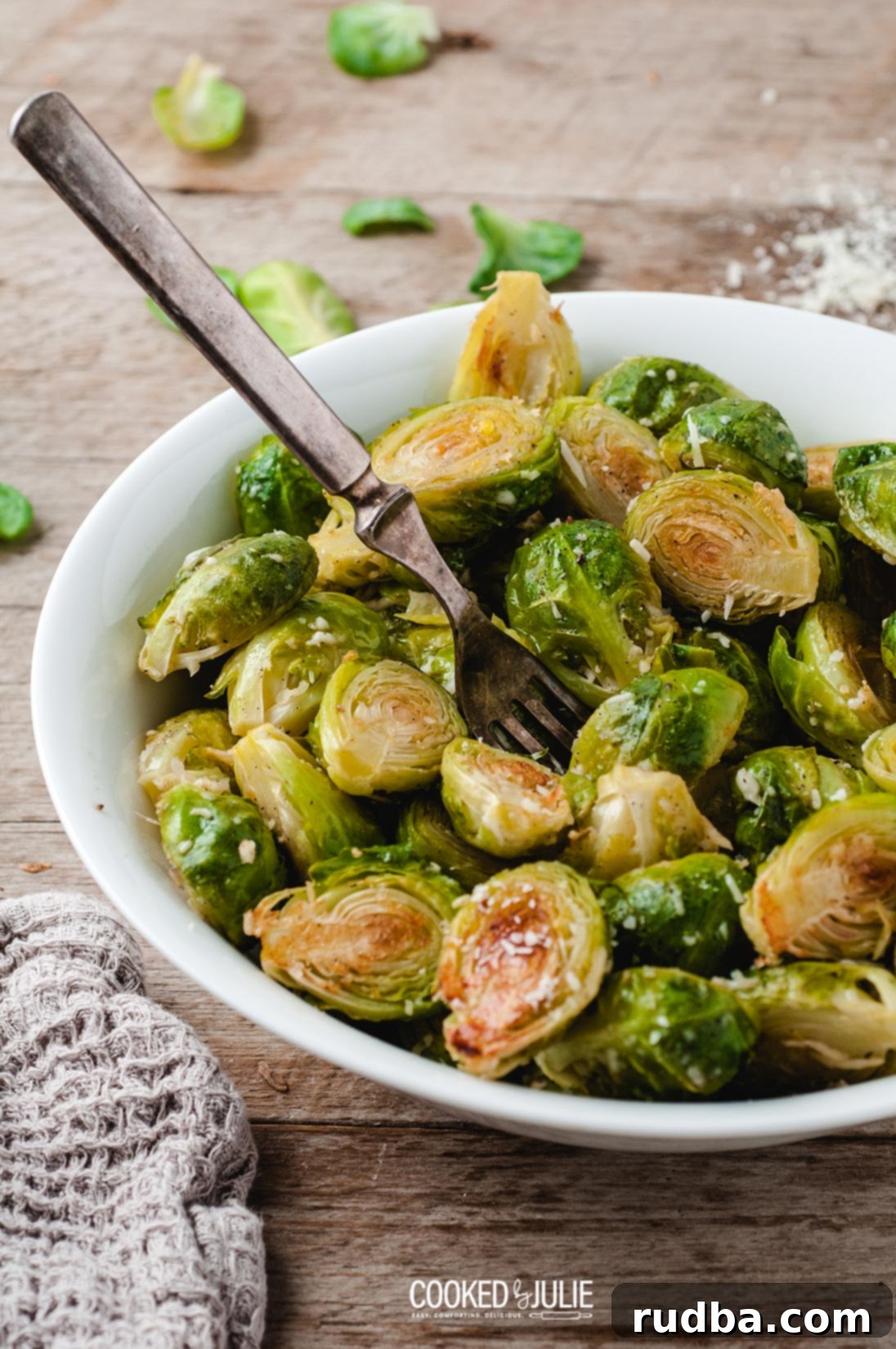 Roasted Parmesan Brussels Sprouts served in a white bowl, garnished with extra parmesan and fresh parsley