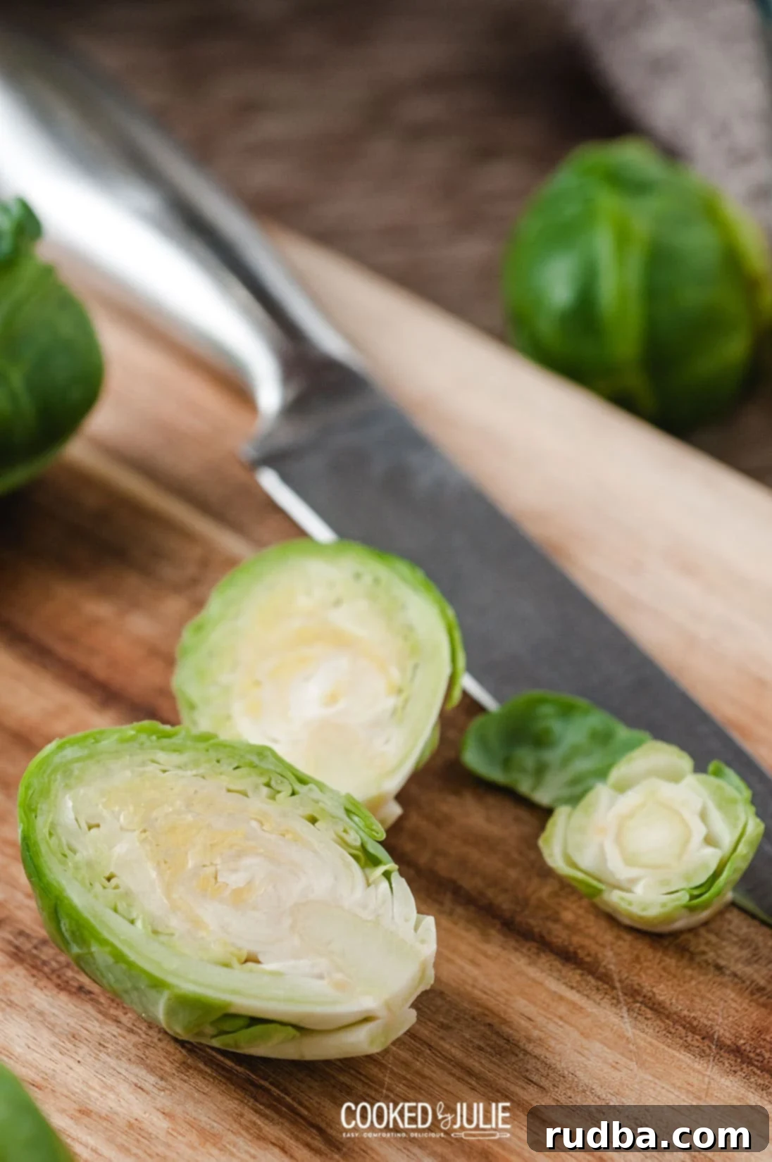 Several Brussels sprouts neatly sliced in half, showing their inner layers, arranged on a wooden board