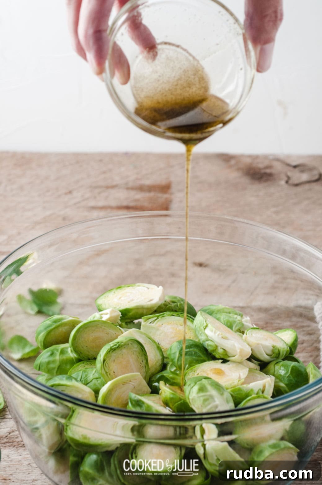 Olive oil being drizzled from a bottle into a small bowl containing salt and pepper