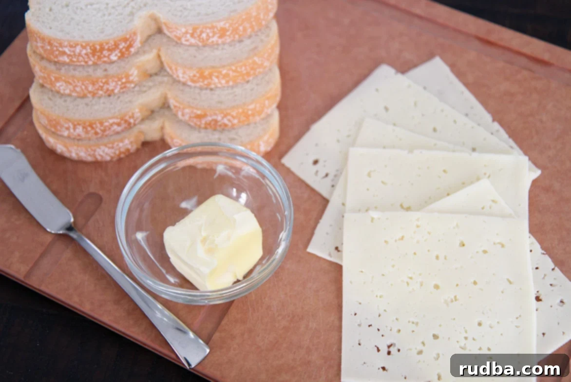 bread, butter, cheese, and a knife on a board, ready for sandwich making