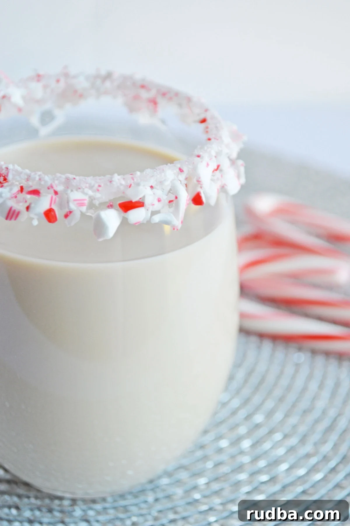Peppermint White Russian in a glass with a candy cane rim, ready to be enjoyed during the holidays