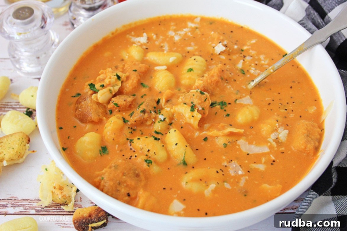 tomato gnocchi soup in a white bowl with croutons on the side
