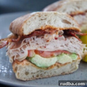 A beautifully presented turkey bacon avocado sandwich on a gray plate, ready to be enjoyed.