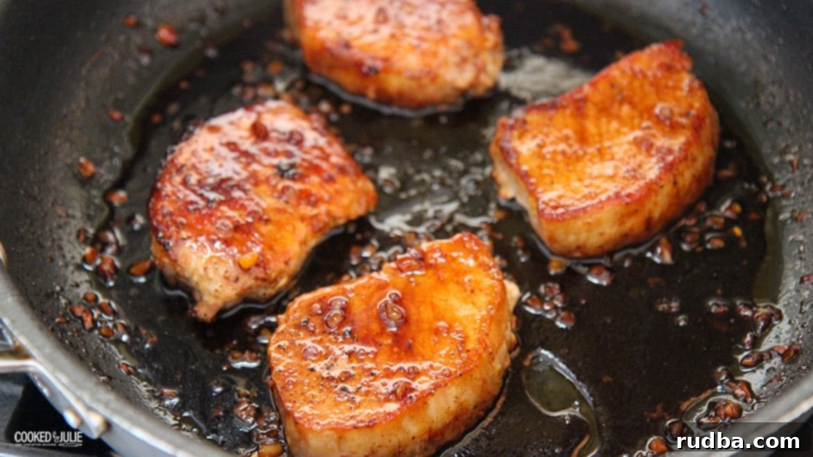 four pork chops with honey sauce in a black skillet garnished with fresh herbs