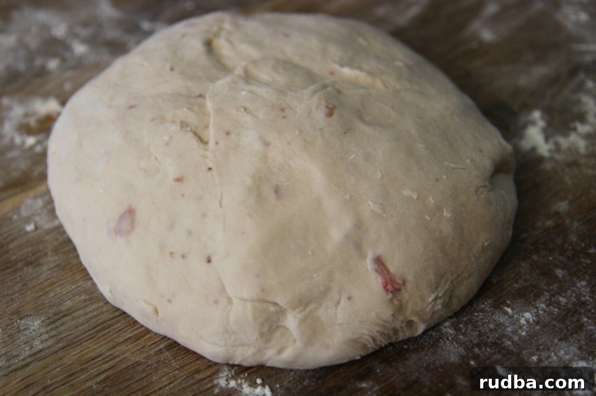 A perfectly risen ball of dough on a wooden floured surface, ready for kneading.